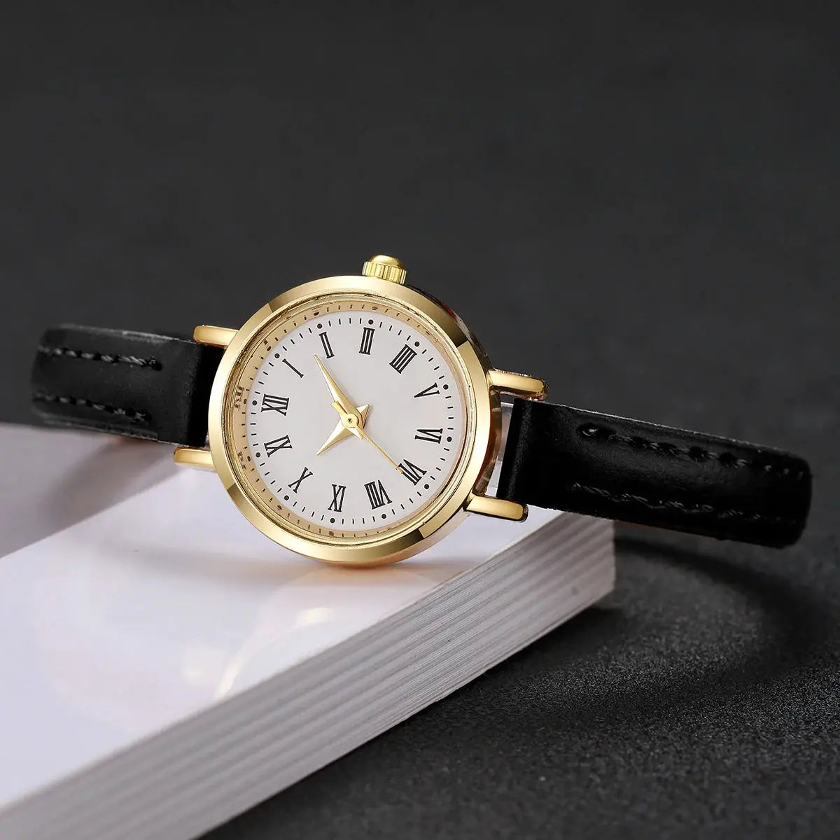Women's watch by Simples Market with a gold-tone case, white Roman numeral dial, and black leather strap