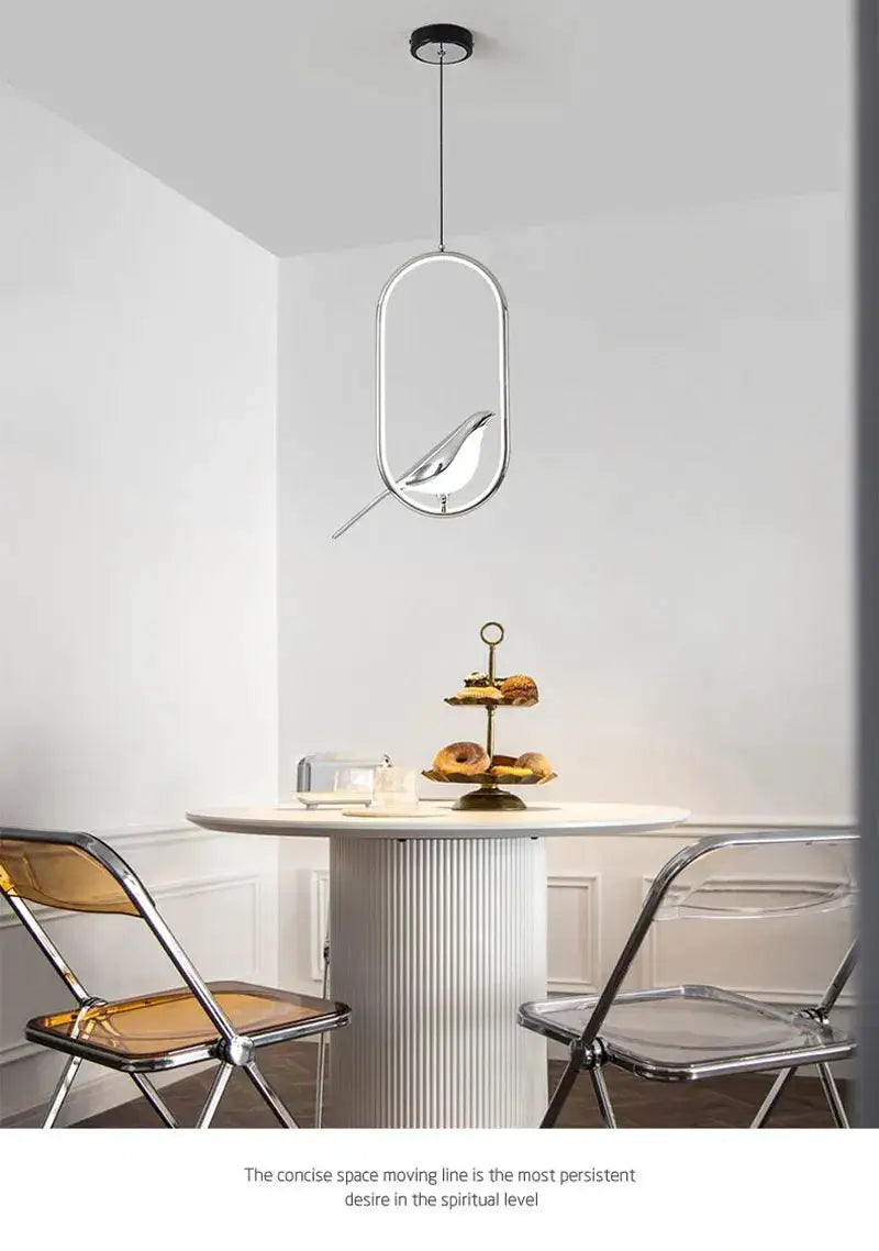 Rotatable magpie LED pendant light with silver oval frame and perched bird, hanging above a dining table.