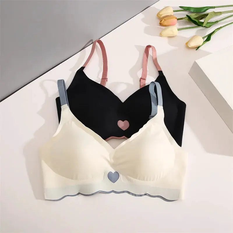 Two seamless bras with adjustable straps; white/cream and black with heart accents, underwire