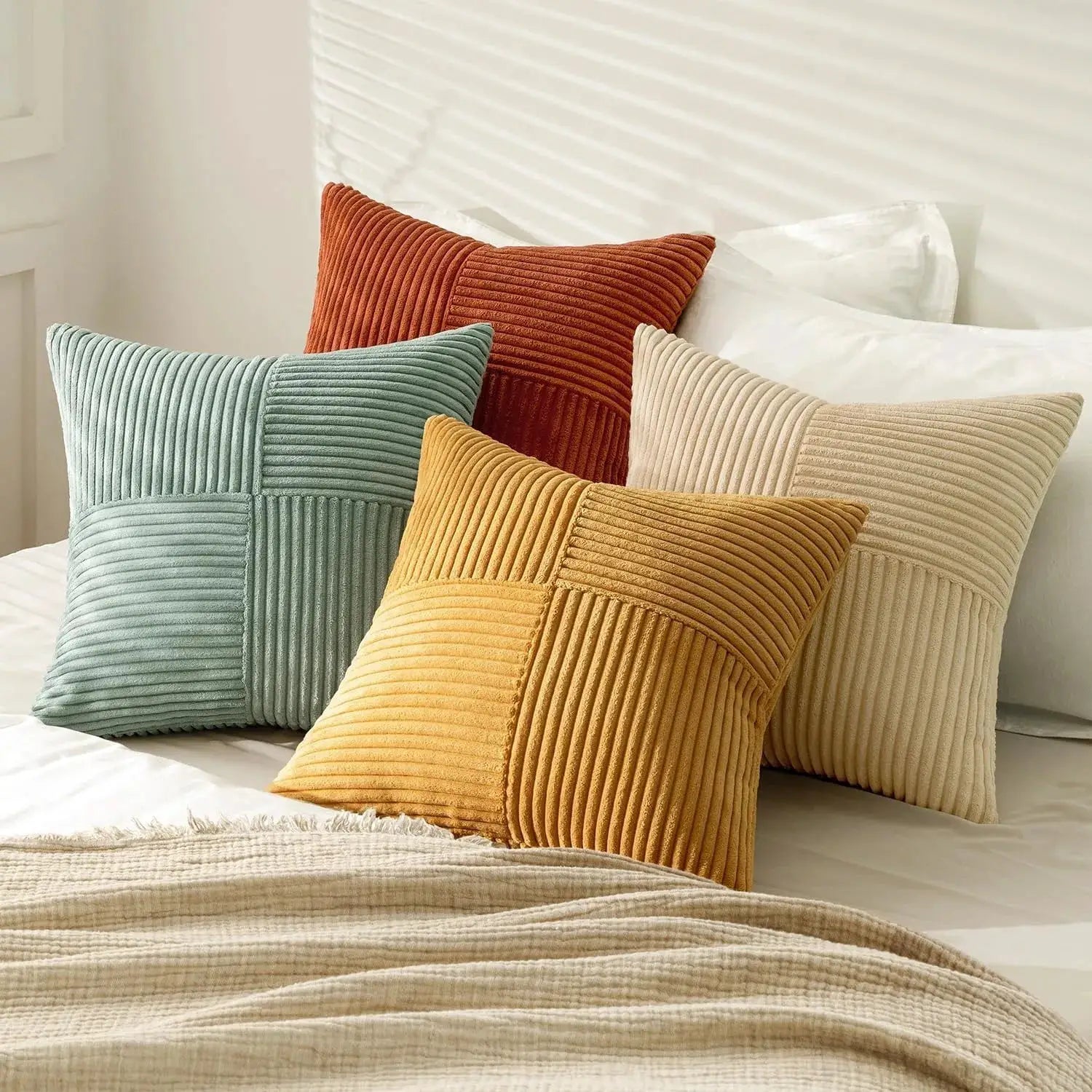 Rust Boho corduroy patchwork throw pillow covers, 18x18, teal, rust, mustard and beige on a bed.