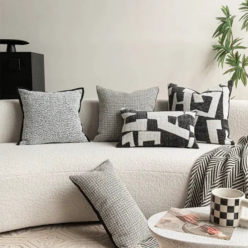 Six decorative pillow covers in ivory and black on a cream sofa with geometric patterns
