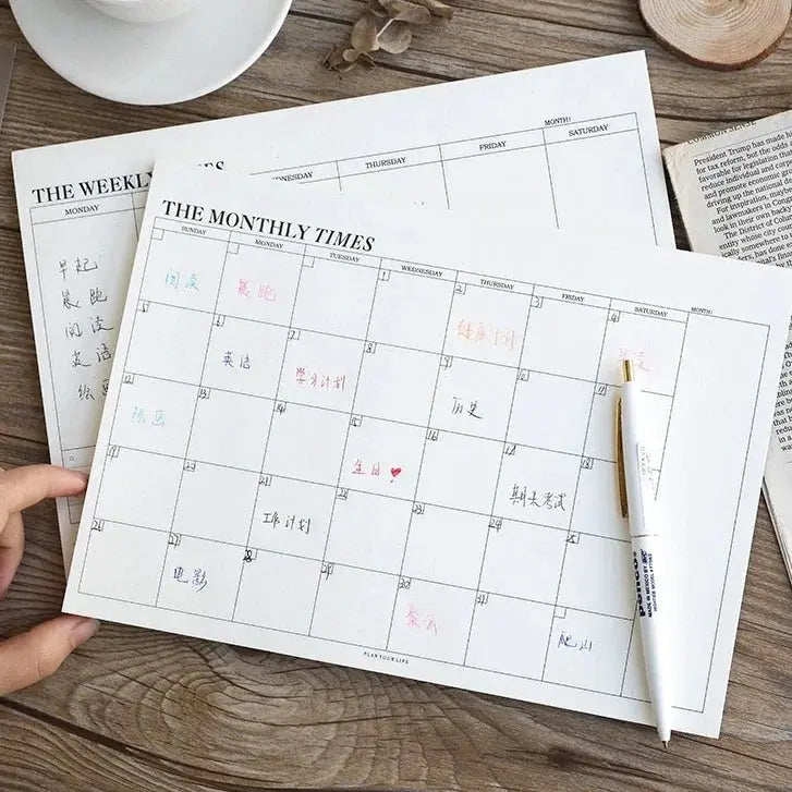 Weekly planner notebook with monthly undated pages and calendar grids on white sheets