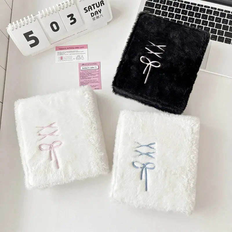 Three plush A6 binder photocard holders in white and black with embroidered bow motifs.