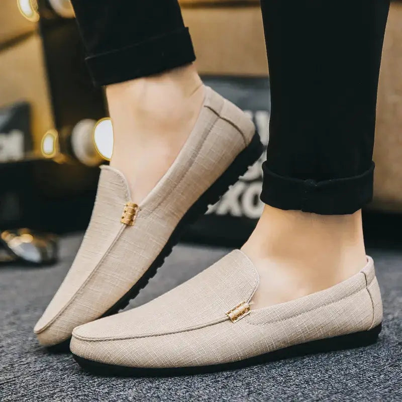 Men's beige canvas slip-on loafers with gold buckle detail.