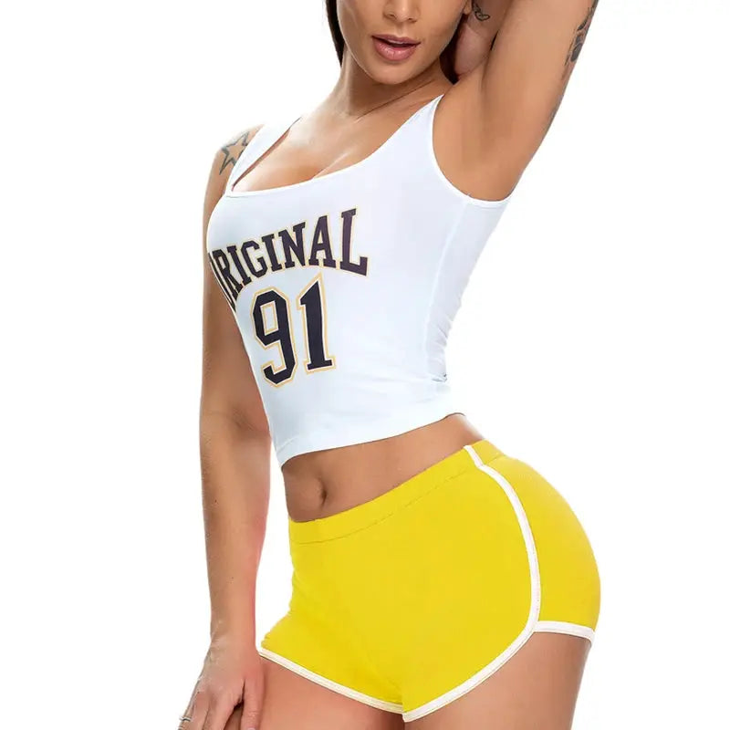 Women’s yellow athletic shorts with white trim, paired with a white cropped tank top.