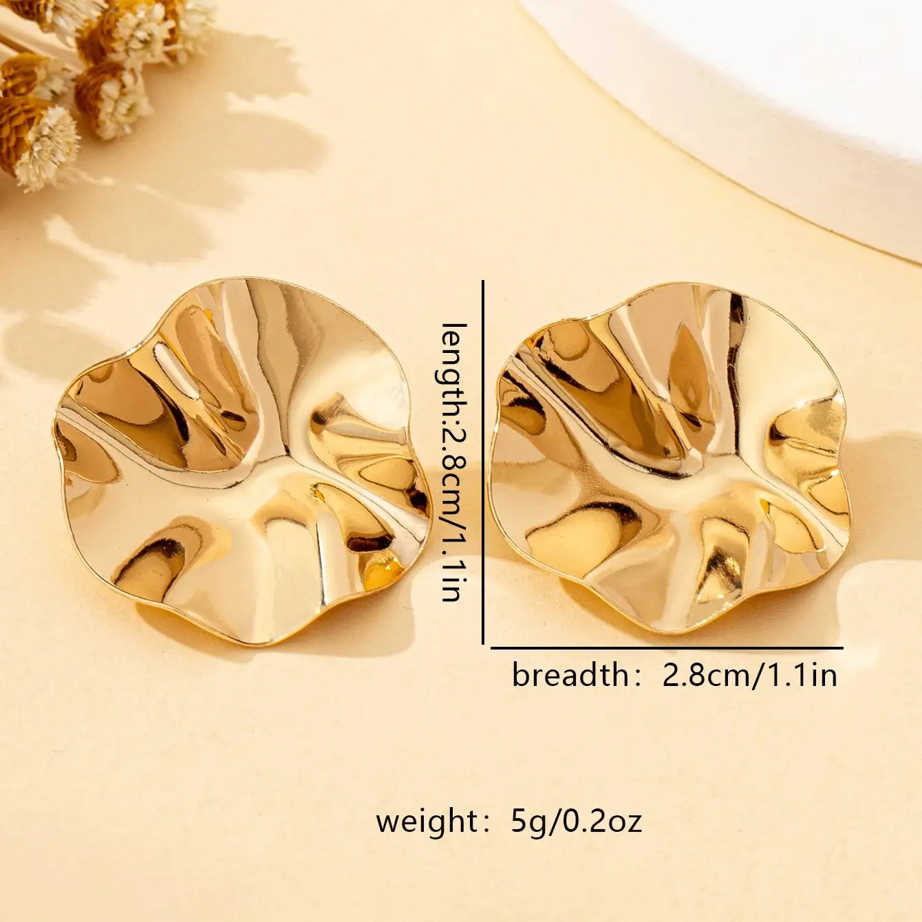 Pair of irregular round gold-tone metal stud earrings with hammered, wavy edges.