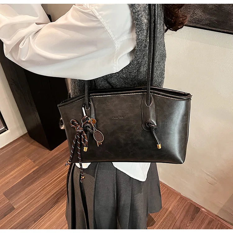 PU leather shoulder bag in black with rope tassel charm and gold hardware