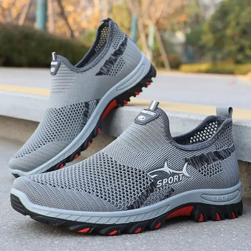 Men's grey mesh slip-on sport sneakers with breathable upper and red-accent outsole.