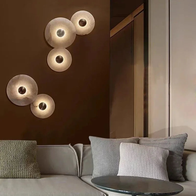 Simples Market luxury Spanish natural marble wall lamp set, five copper-centered discs with warm LED glow above a gray sofa.