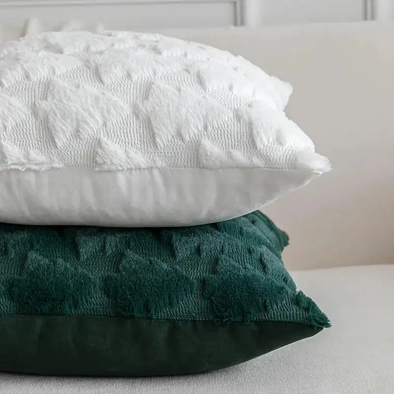 3 decorative pillow covers stacked: white textured, emerald green velvet, dark green cushion