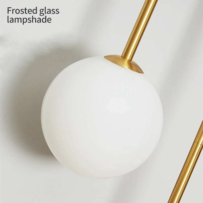 Modern wall lamp with frosted glass ball shade and gold metal stem.