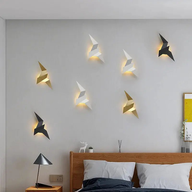 LED bird wall lamps by Simples Market; white, gold, and black geometric wall lights with warm backlight above the bed