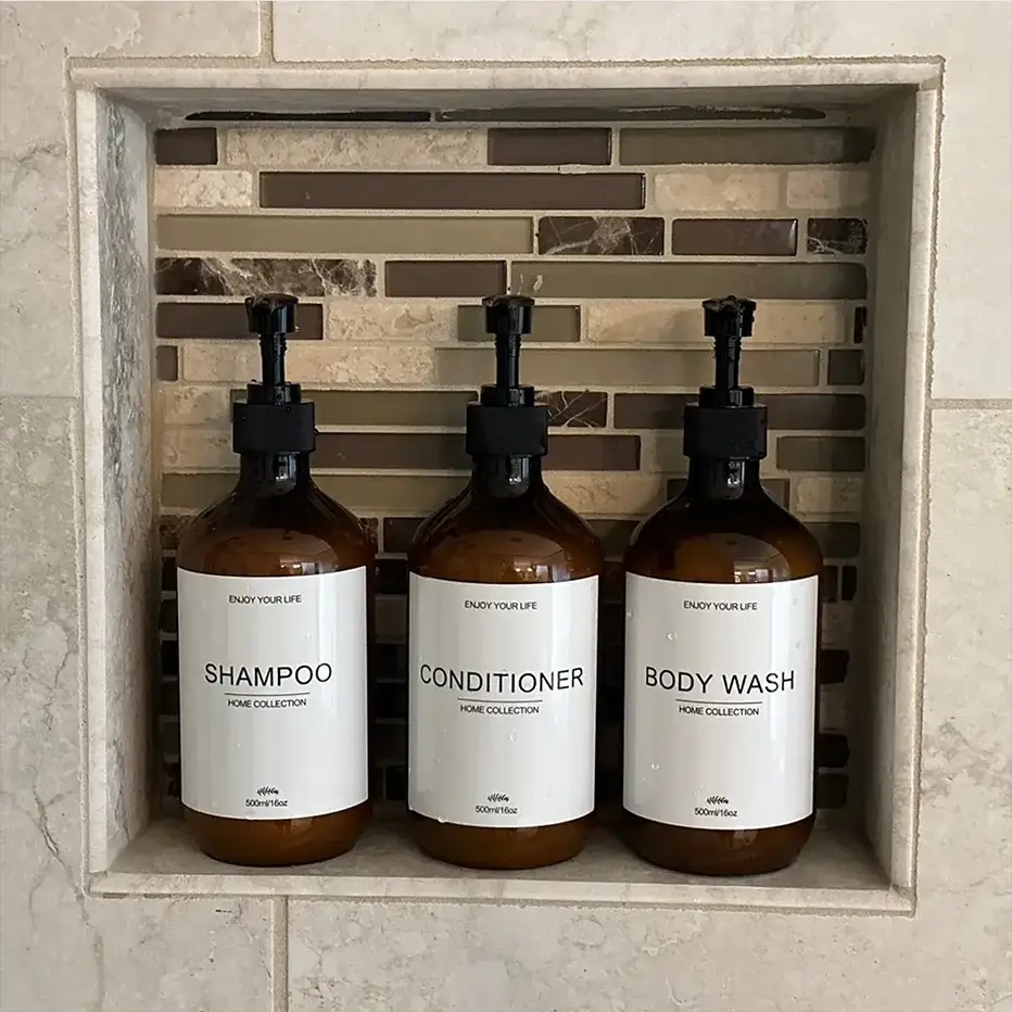 Three amber 500ml pre-labeled dispenser bottles with black pumps for shampoo, conditioner, and body wash.