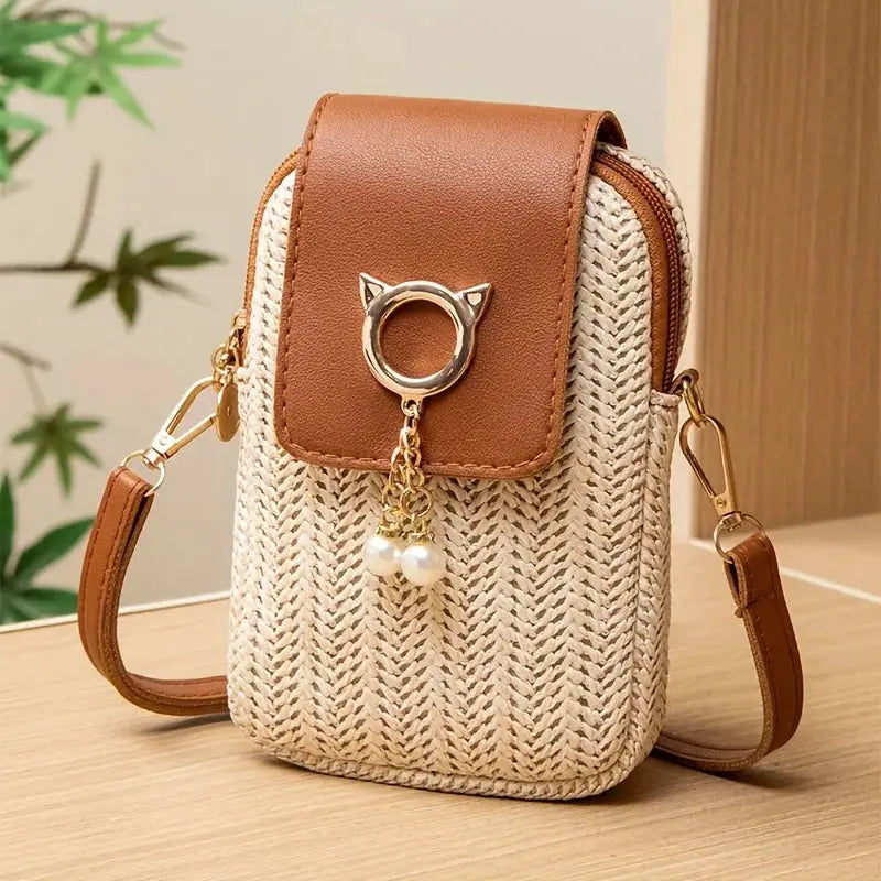 Casual street style mini crossbody phone bag with woven straw body, brown leather flap, gold ring clasp and pearl tassel