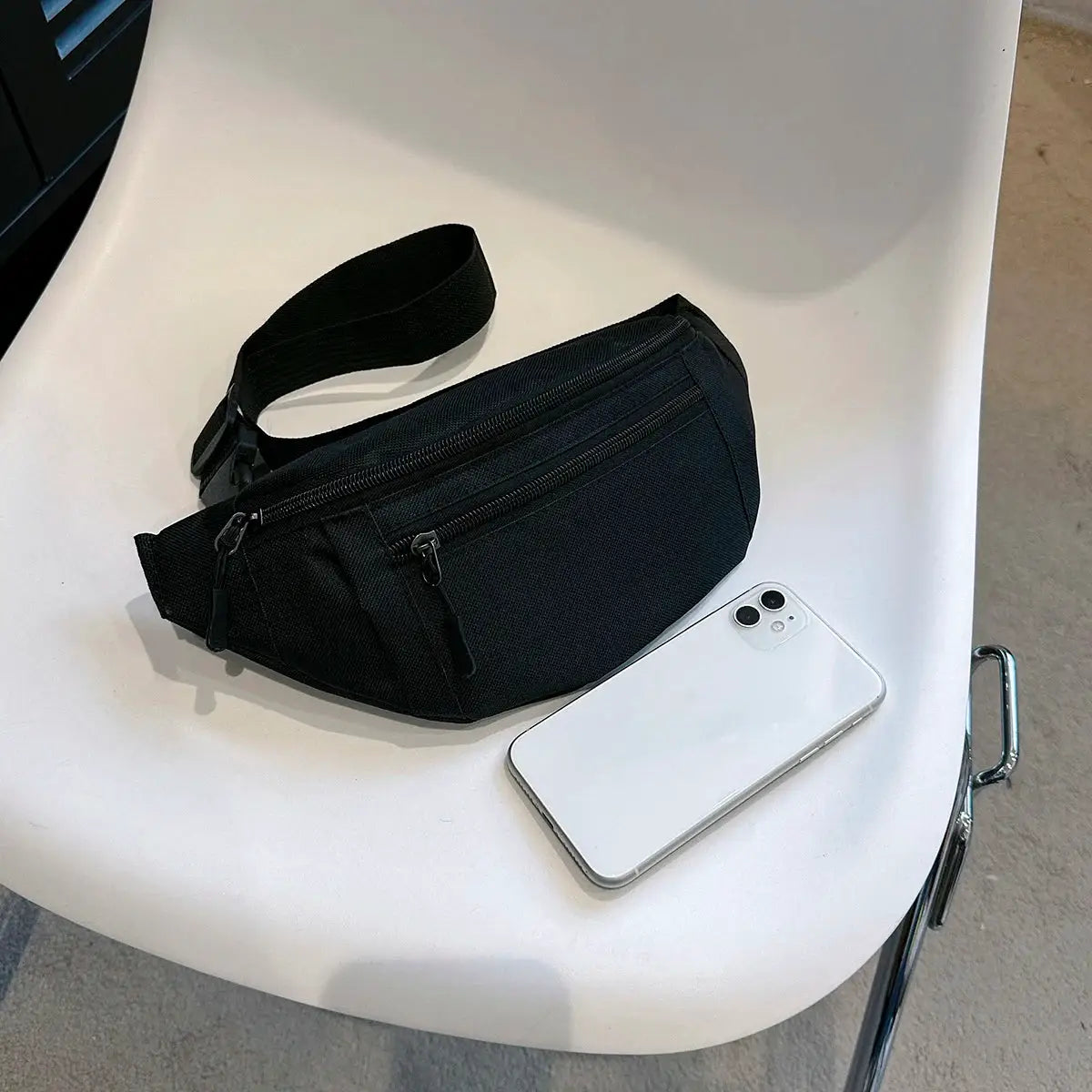 Simples Market black fanny pack waist bag with dual zip pockets and adjustable strap, shown beside a smartphone