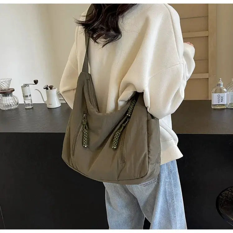 Trendy women's soft cloth shoulder bag in taupe with dual zip pockets and green braided zipper pulls worn crossbody