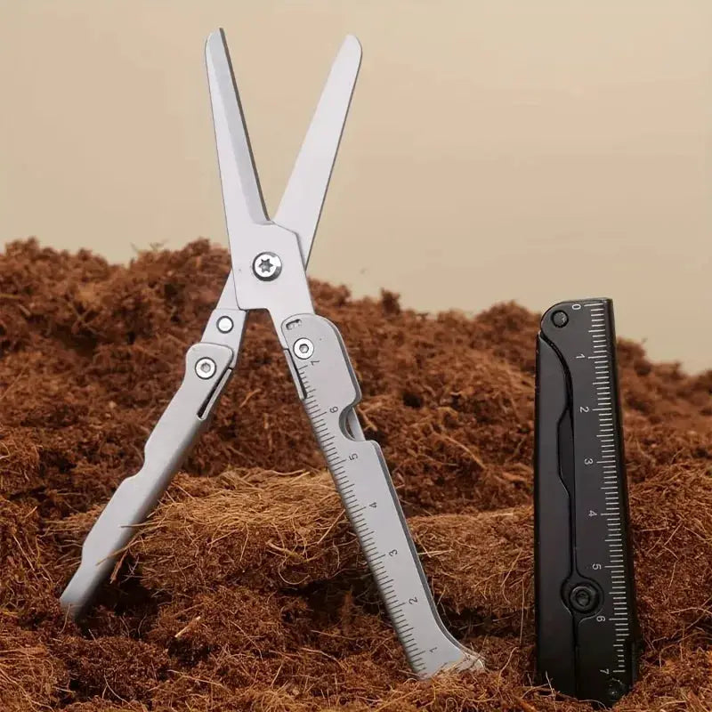 Portable multifunctional folding scissors in stainless steel, shown beside a black ruler