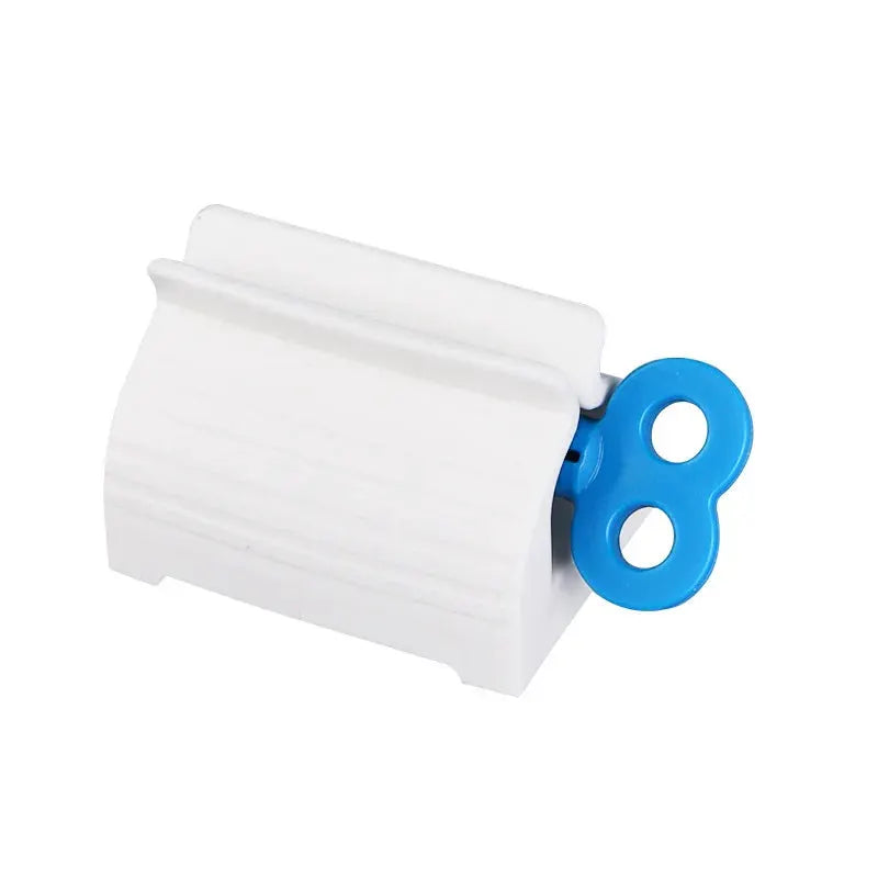 Simples Market toothpaste tube squeezer, white plastic body with blue circular handle.