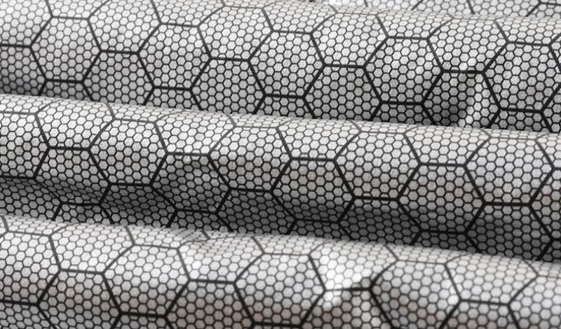 Jacket fabric with gray and white honeycomb hexagon pattern; quilted textile texture.
