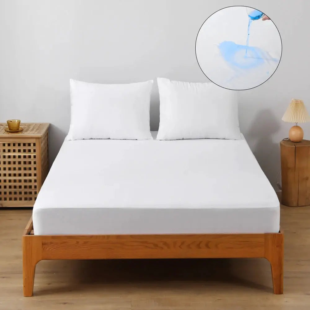 Waterproof mattress protector cover, white knitted fitted sheet on a wooden bed; breathable and ultra-soft, 2 pillows.