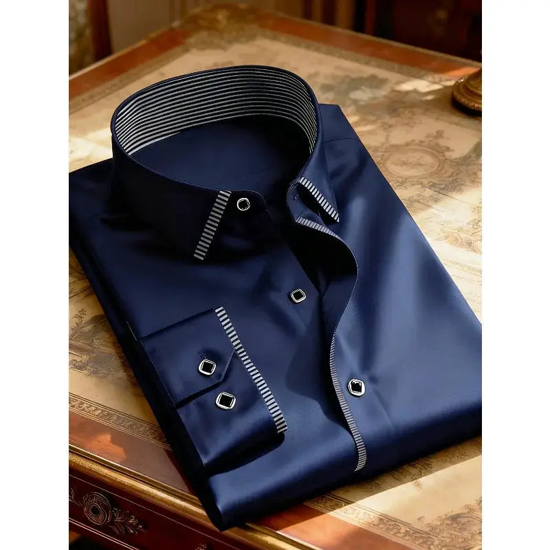 Navy blue men's long-sleeve dress shirt with striped inner collar and cuffs, folded on table.
