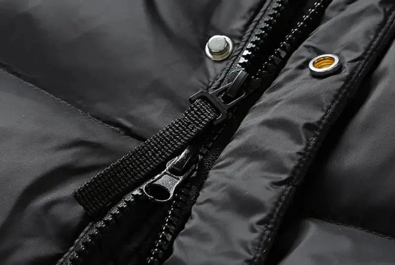 Men's black hooded down jacket close-up of front zipper and metal snaps on a puffer coat.