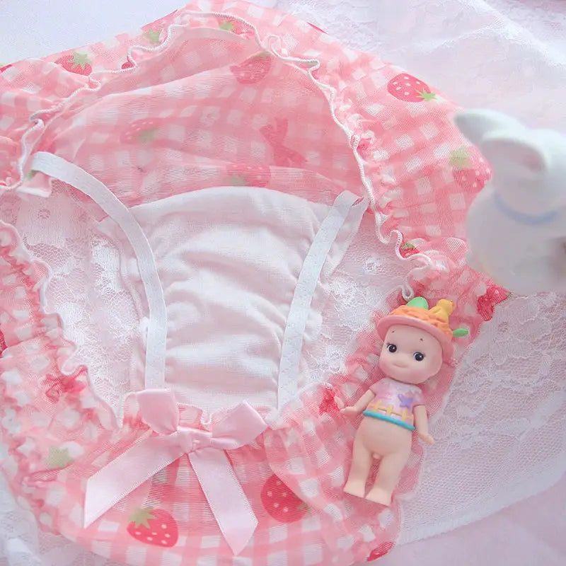 Pink strawberry-print mesh panties with bow and lace trim; tiny doll beside