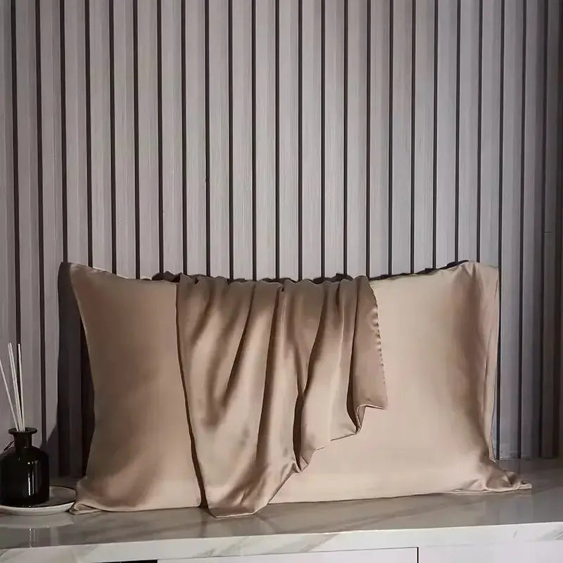 Simples Market Nordic Silk pillowcase set in beige silk on a bed with a gray striped wall