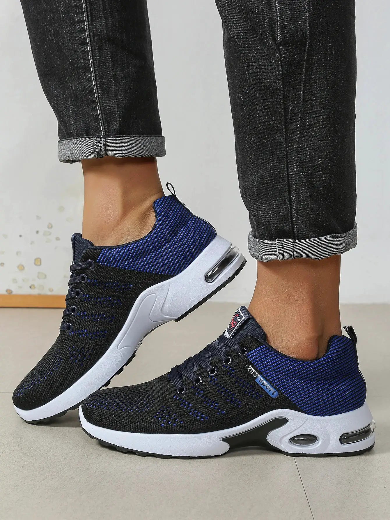 Men's running shoes; black and blue knit upper, lace-up design, white cushioned sole.