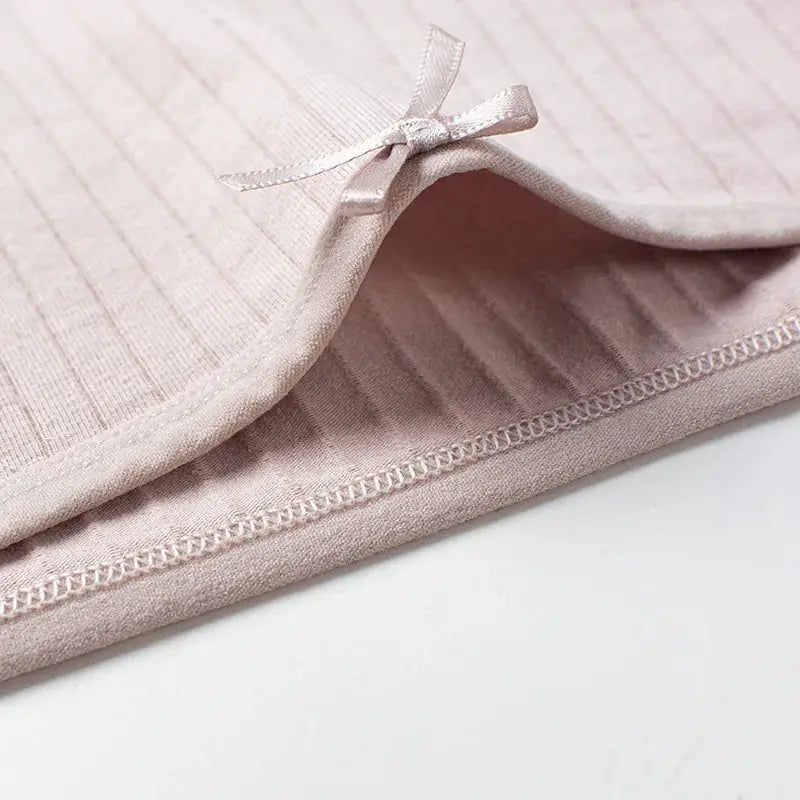 Panties: light pink cotton ribbed mid-rise briefs with a small bow detail, close-up stitching.