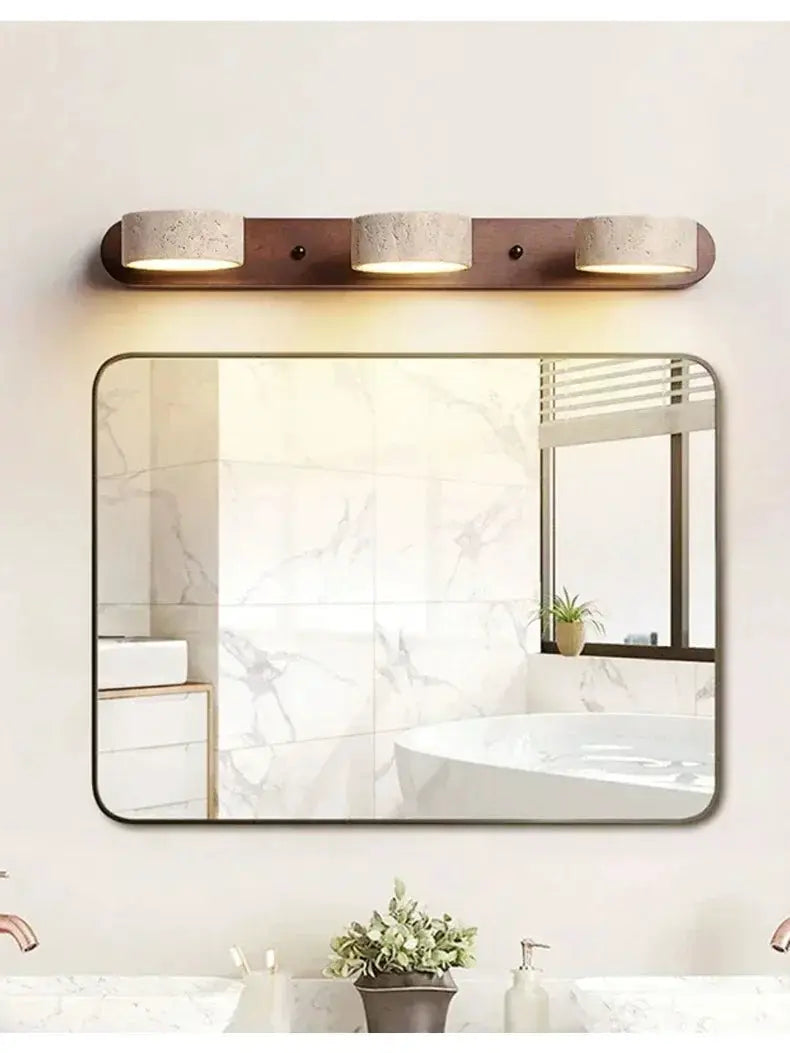Round LED wall light with a wooden backplate and three warm lamps above a rounded bathroom mirror.