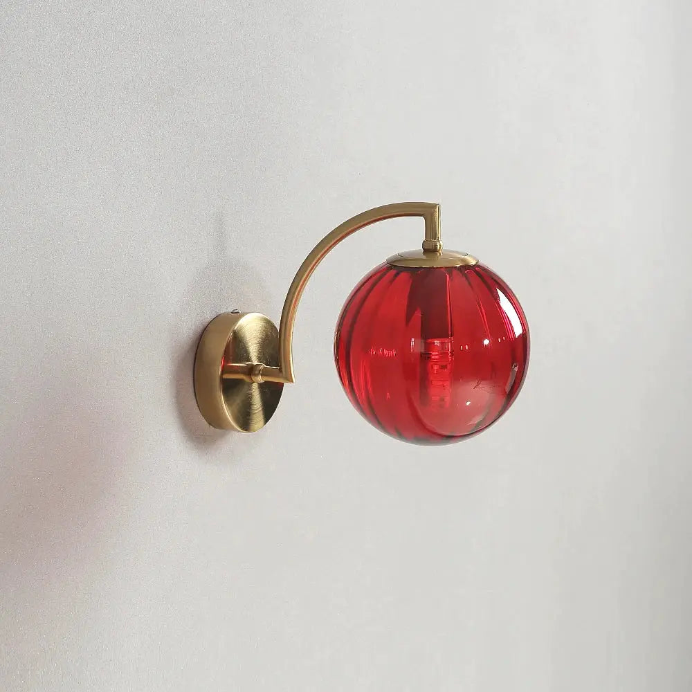 LED wall lamp with brass curved arm and red glass globe shade for bedroom or living room
