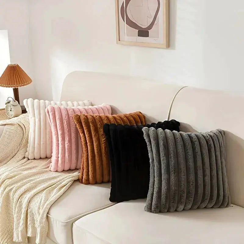 Five stripe corduroy pillow covers in white, pink, tan, black, and gray on a cream sofa