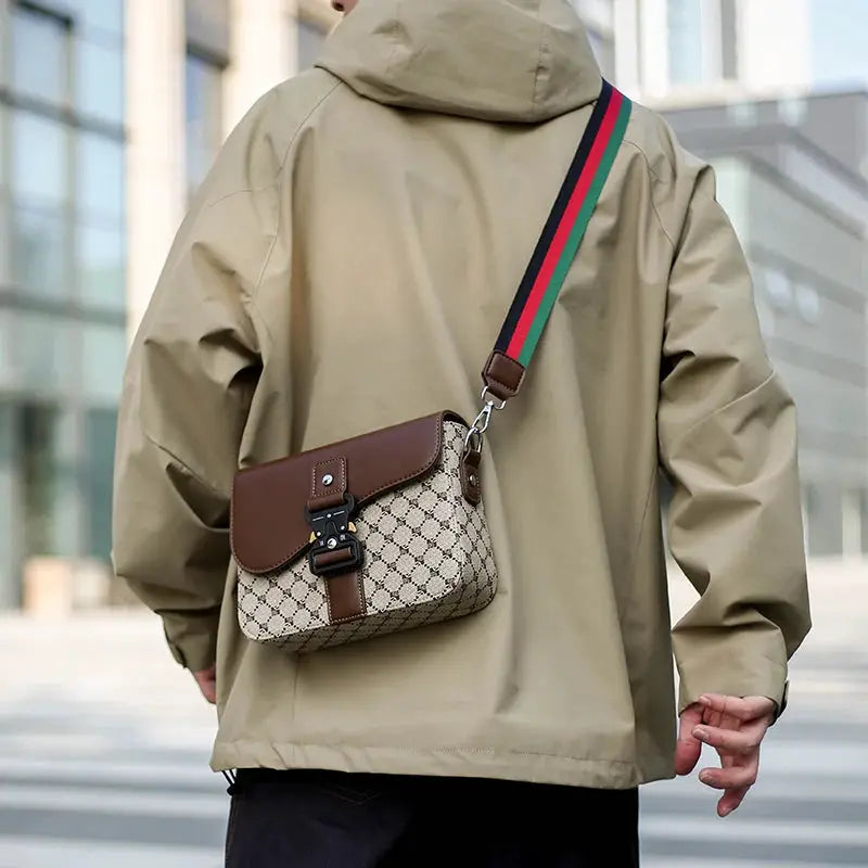 Crossbody bag with beige jacquard fabric and brown leather flap; green-red-green striped strap for commuting.
