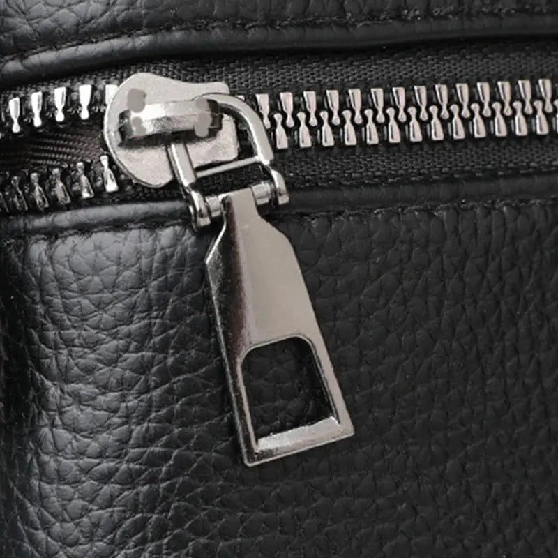 Simples Market PU leather crossbody bag in black; close-up of metal zipper pull on textured grain, durable hardware
