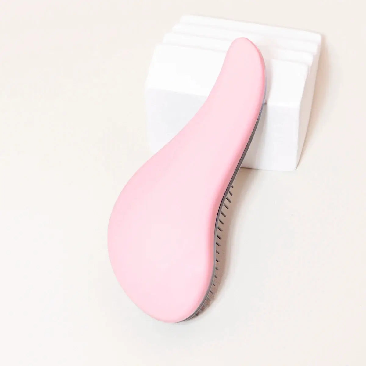 Pink antistatic massage brush with curved handle and gray bristle edge for wet hair and wigs