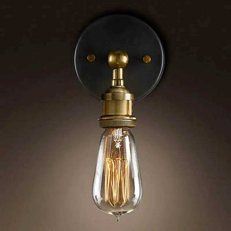 American single-head brass wall lamp with an exposed Edison bulb on a round dark backplate.