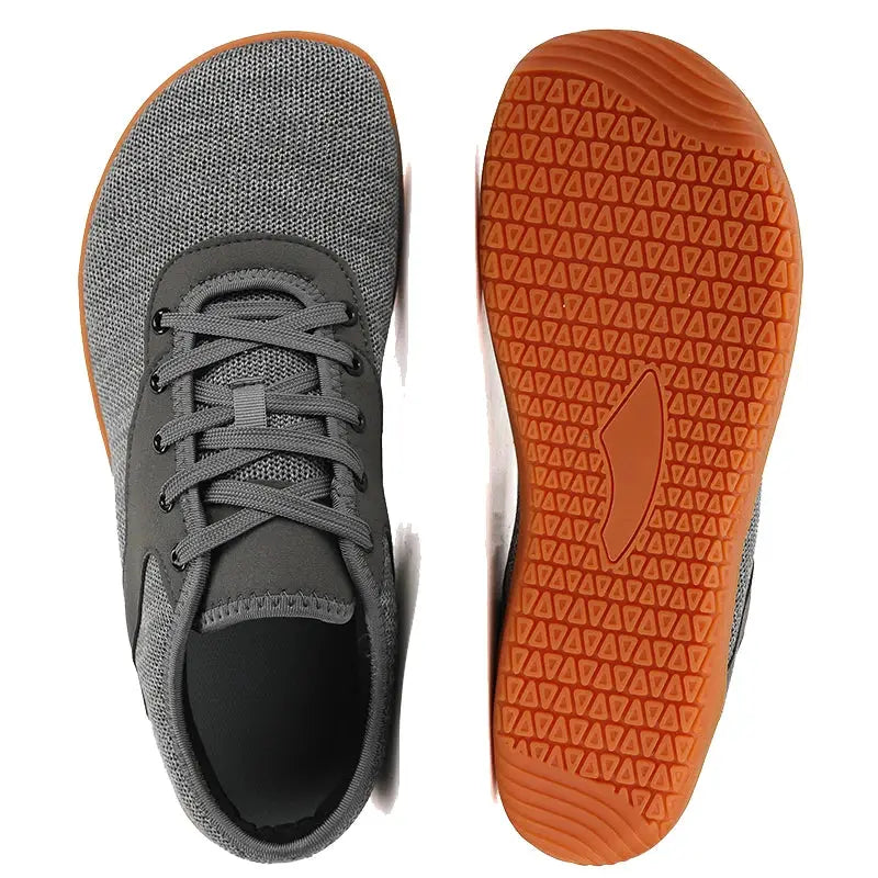 Pair of grey trail running shoes with breathable mesh uppers and orange rubber outsoles