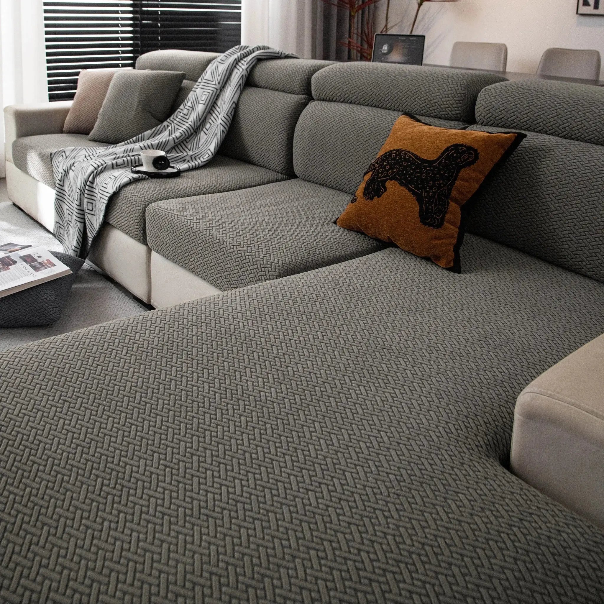 Stretchy polar fleece sofa cover for 4-seat sofa in gray with geometric pattern, shown with cushions
