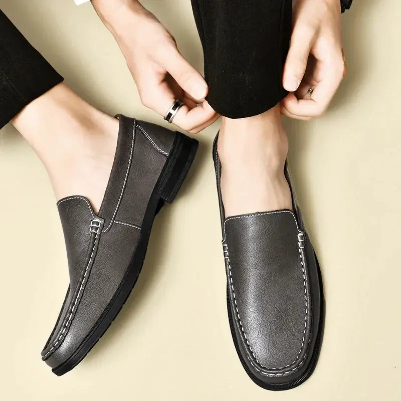 Leather men's slip-on dress shoes in grey with white contrast stitching; two shoes shown.