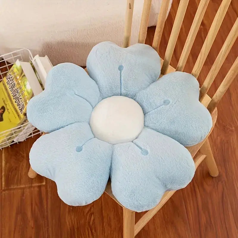 Flower-shaped plush throw pillow by Simples Market, light blue petals with white center on a wooden chair