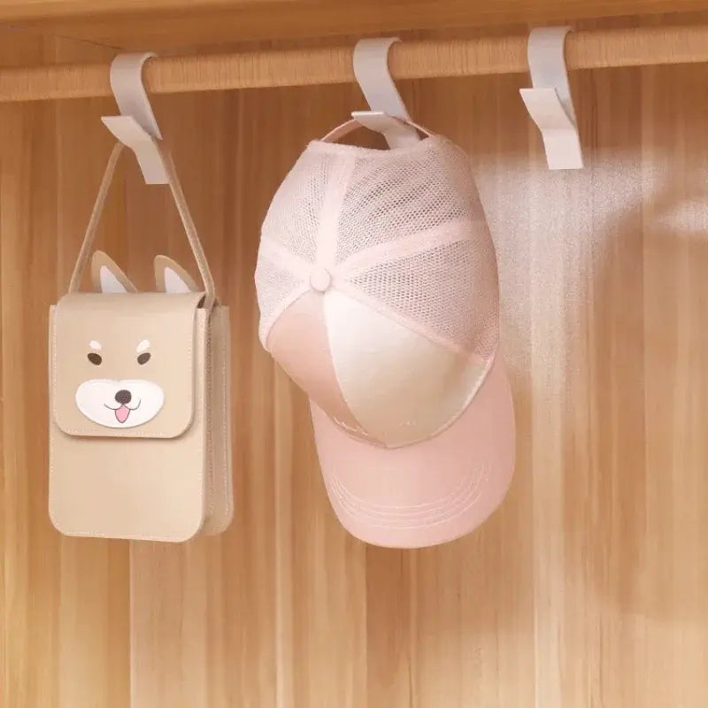 Bathroom towel rail hooks on a wooden rod; beige mini bag with bunny face and pink cap hanging
