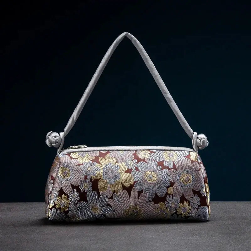 Shoulder bag by Simples Market with embroidered floral satin in maroon and a gray strap.
