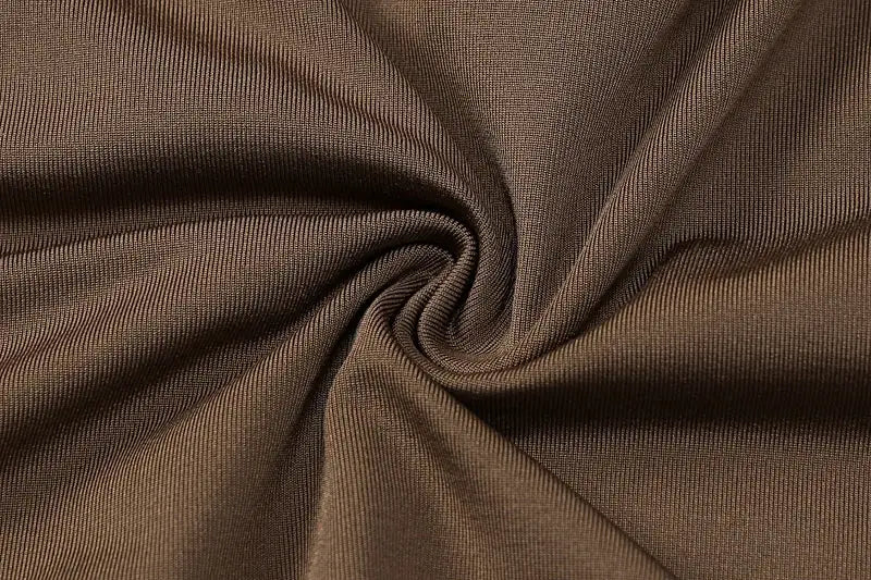 Brown stretch knit fabric close-up with twisted fold and fine rib texture