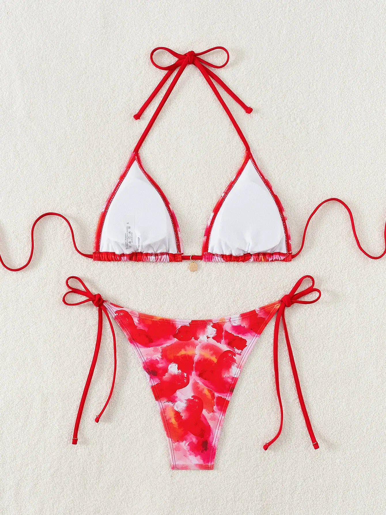 Triangle bikini set with red trim and ties, white triangle cups, and floral print Brazilian-cut bottoms