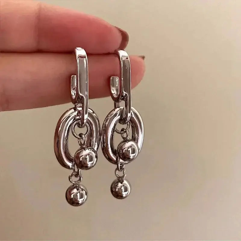 Silver-tone hoop earrings with stacked rings and small dangling spheres