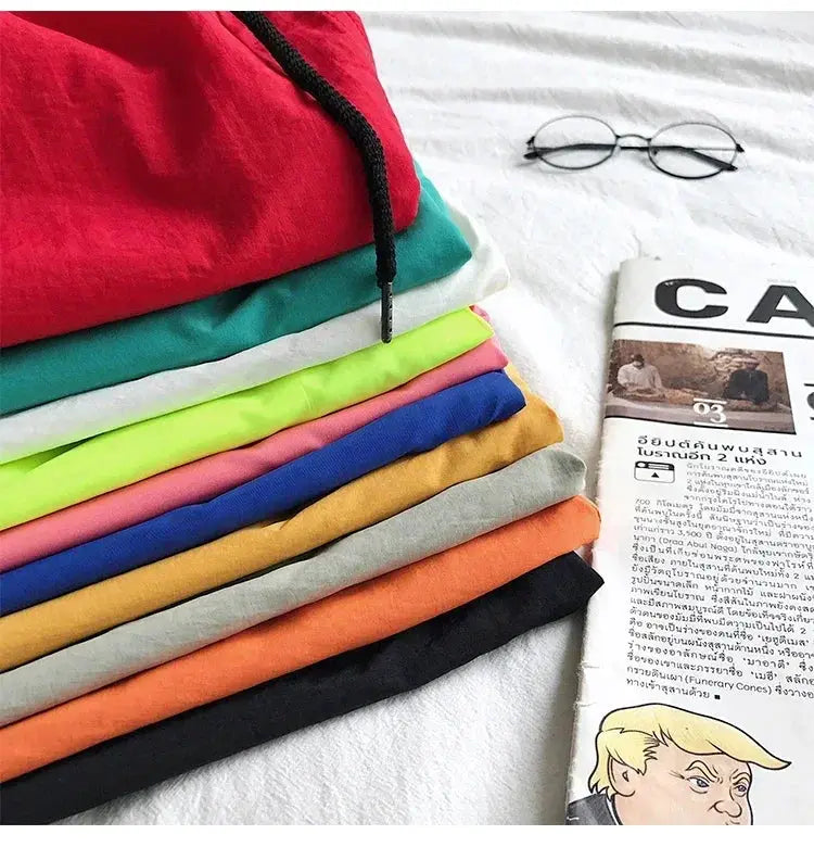 Men's swim shorts in an assortment of colors, neatly folded stack with glasses and a newspaper nearby