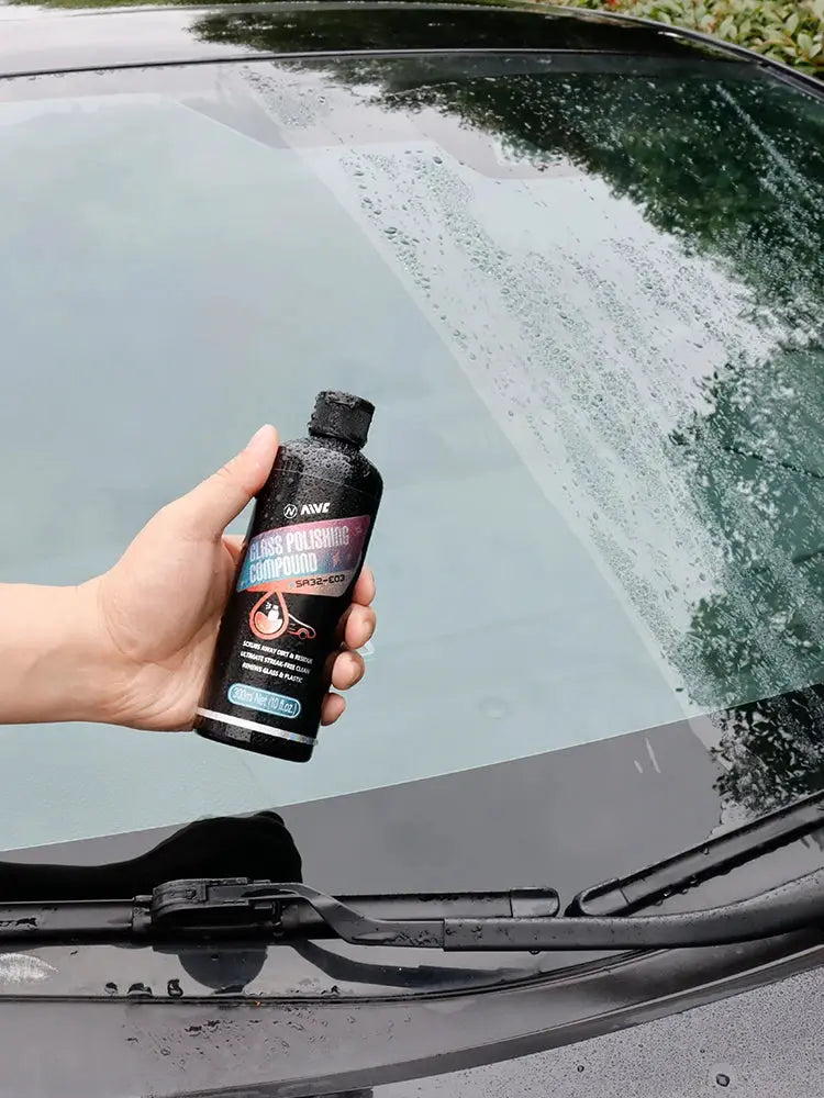 Simples Market black glass polishing compound bottle held next to a car windshield for auto detailing.