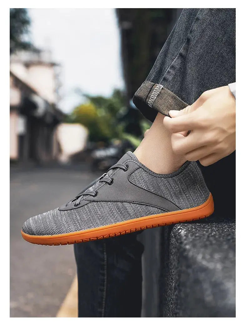 Simples Market men's minimalist trail running shoe with gray knit upper and orange outsole