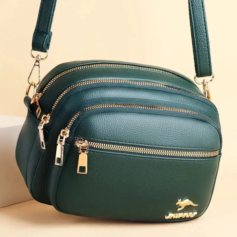 Leather shoulder bag in teal by Simples Market with multiple zip pockets and gold-tone hardware
